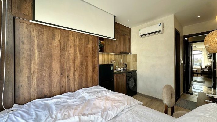 Phòng cho thuê có màn chiếu thả trần, vách gỗ, giường và đèn thả mây